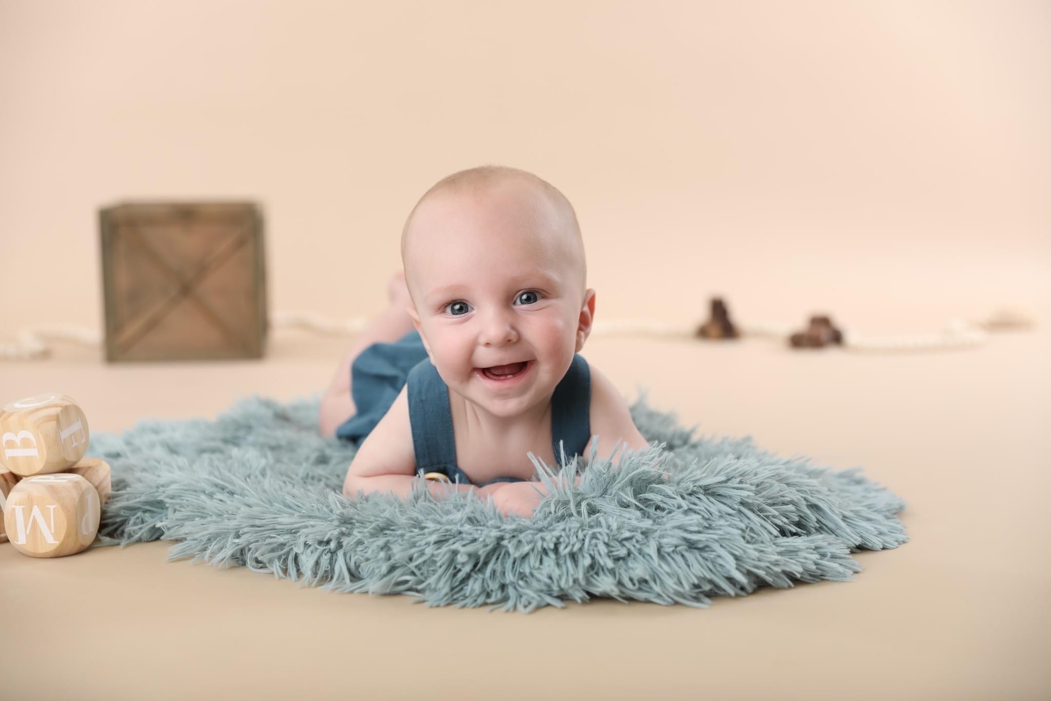 Baby on its tummy smiling in a photoshoot